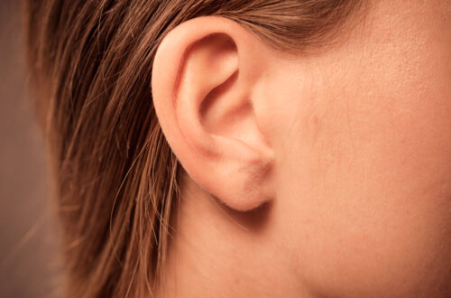 Nahaufnahme eines menschlichen Ohrs von der Seite, mit weichem Haar im Hintergrund. Das Bild zeigt die Form und Struktur des Ohrs, ideal für Themen wie Anatomie oder Hörgesundheit.