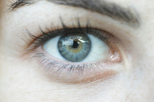 Nahaufnahme eines menschlichen Auges mit einer einzigartigen irisen Farbkombination aus Blau und Grün, umgeben von langen Wimpern und heller Haut. Ideal zur Veranschaulichung von Augenfarbe und Detailgenauigkeit.