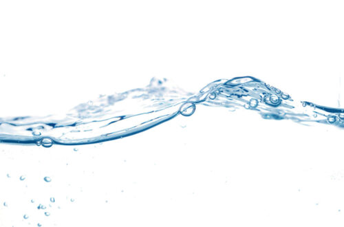 Wasseroberfläche mit Wellen und Luftblasen vor hellem Hintergrund, die die Klarheit und Reinheit des Wassers darstellen.