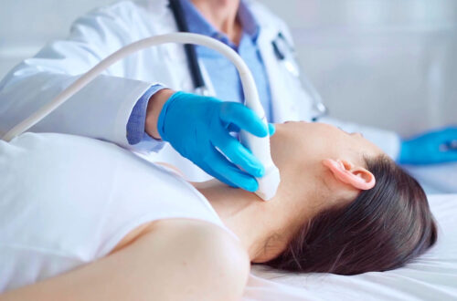 Ultraschalluntersuchung im medizinischen Kontext: Ein Arzt führt einen Ultraschall an einer Patientin durch, die auf einer Liege liegt. Die Hand des Arztes ist mit einem blauen Handschuh bedeckt und hält das Ultraschallgerät.